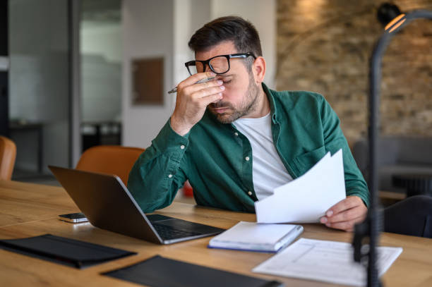 Stressed business owner reviewing documents at desk